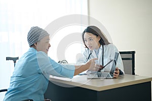 Cancer patient woman wearing head scarf after chemotherapy consulting and visiting doctor in hospital