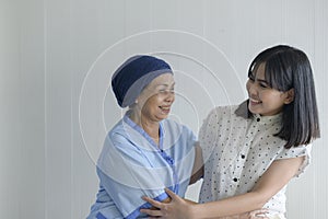 Cancer patient woman wearing head scarf and her supportive daughter in hospital, health and insurance concept