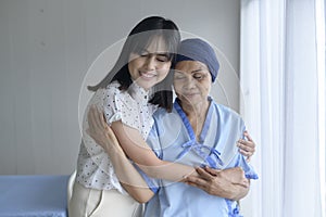 Cancer patient woman wearing head scarf and her supportive daughter in hospital, health and insurance concept