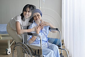 Cancer patient woman wearing head scarf and her supportive daughter in hospital, health and insurance concept