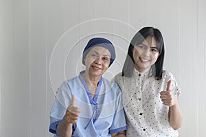 Cancer patient woman wearing head scarf and her supportive daughter in hospital, health and insurance concept