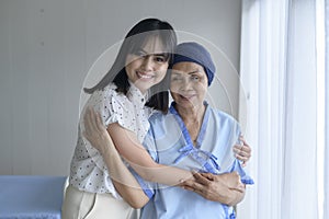 Cancer patient woman wearing head scarf and her supportive daughter in hospital, health and insurance concept