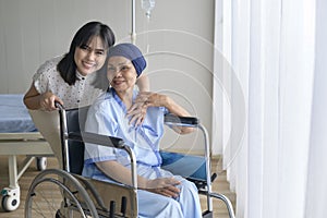Cancer patient woman wearing head scarf and her supportive daughter in hospital, health and insurance concept