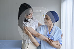 Cancer patient woman wearing head scarf and her supportive daughter in hospital, health and insurance concept