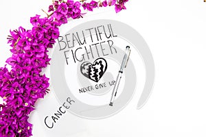 Cancer word written on note with pen and wild purple flowers. Beautiful fighter inspirational card.