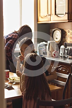 Candid asian family mother and two daughters in kitchen at home in backlight, cozy apartment lifestyle, selective focus