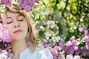 Candid authentic portrait of 30s 40s caucasian blonde woman with lilac flowers. 30 40 year old woman enjoying life in