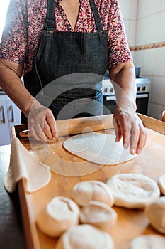 Candid Capture of Unidentified Latina Woman Crafting Dough with Hands and Rolling Pin in Rustic Home Kitchen photo