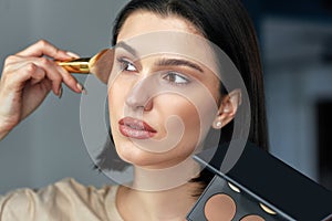 Candid closeup portrait of a brunette young woman making makeup herself