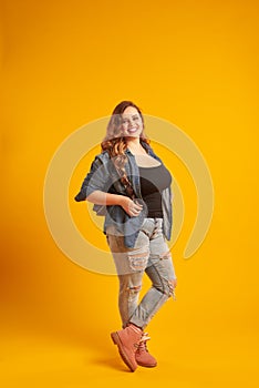 Candid curvy girl in denim jacket holding backpack and looking a