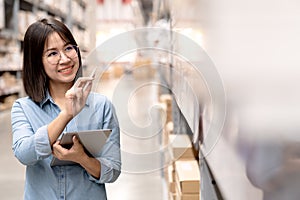 Candid or headshot of young happy attractive asian employee or staff working in store inventory in warehouse using computer tablet