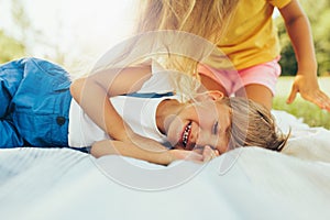 Candid image of happy children playing on the blanket outdoors. Happy little boy and cute little girl relaxing in the park. Kids