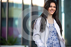 Candid lifestyle portrait of a female medical professional in a white coat walking outside workplace