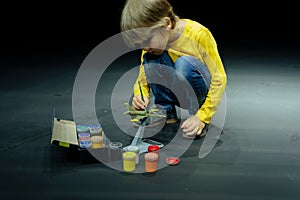 candid little six year old kid boy painting or colorize or colour model airplane with gouache paints