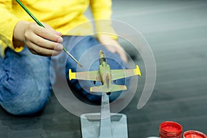 candid little six year old kid boy painting or colorize or colour model airplane with gouache paints