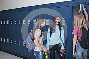 Junior High school Students talking and standing by their locker in a school hallway photo