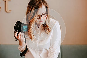 Candid portrait of beautiful blonde girl woman photographer with her camera at work