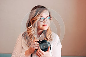 Candid portrait of beautiful blonde girl woman photographer with her camera at work