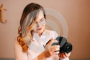 Candid portrait of beautiful blonde girl woman photographer with her camera at work