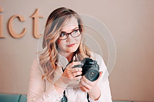 Candid portrait of beautiful blonde girl woman photographer with her camera at work