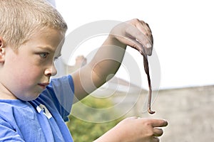Candid portrait of boy playing with a worm photo