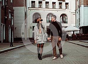 Candid portrait of fashionable couple. Man and woman watching to each other on background of city street. Autumn dating. Love and