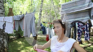 Candid real life portrait of young adult beautiful attractive caucasian woman hanging up fresh washed family clothes on