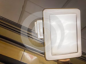 A candid reflection on an escalator, focusing on a sign attached to the handrail titled A HANDBOOK FOR THE INITIATED photo