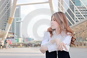Candid shot of attractive young Asian business woman thinking and dreaming about something at city background.