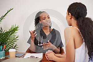 Candid shot of Black female doctor explaining to patient during GP consultation
