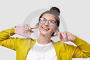 Candid shot of brunette pretty smiling young woman using cellphone, to listening the music.