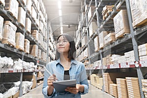 Candid of young attractive asian woman auditor or trainee staff work looking up stocktaking inventory in warehouse store by