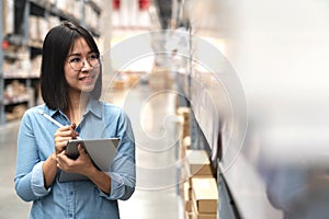 Candid of young attractive asian woman, auditor or trainee staff working in warehouse store counting or stocktaking inventory by