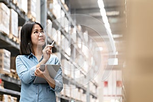 Candid of young attractive asian woman, auditor or trainee staff working in warehouse store counting or stocktaking inventory by photo