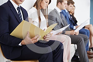 Candidates waiting for job interviews, mid section photo