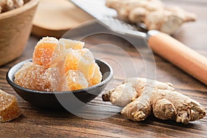 Candied ginger pieces and ginger roots on wooden table. Healthy sweets