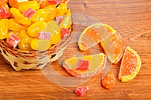 Candies and jellies in basket on wood