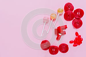 candies and red lollipops on a plain pink background. wallpaper to use text. graphic resource.