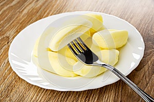 Candies in shape of bananas in plate, candy strung on fork on table