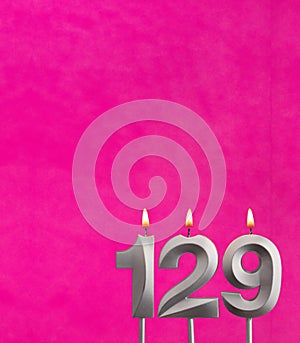 Candle 129 with flame - Birthday card in fuchsia background