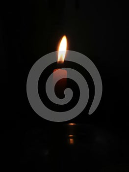 A candle is afire, aflame in a black background
