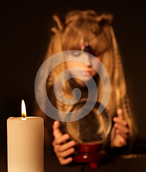 Candle against the girl holding crystal ball.