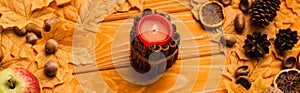 Candle with autumnal decoration on wooden