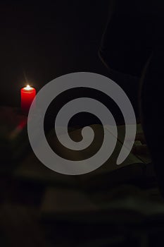 Candle and a book of the Bible on wooden background at night