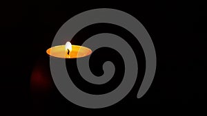 Candle burning with quivering shaking flame and wind blowing but can`t extinguish it isolated on a black background