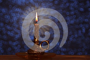 Candle burns with a bright flame in a candlestick in a dark room, the concept of magic, prayer, spiritualism, mourning