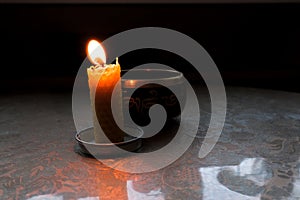 candle burns near Tibetan bowl