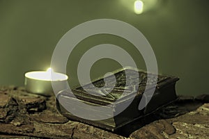 candle burns on tree bark on candle burning day with bookplate in leather binding photo