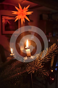 candle on the christmas tree with a christmas star in the background