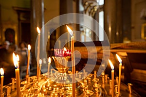 candle church. A row of lighted wax candles in the Christian Orthodox Church on a dark blurred background